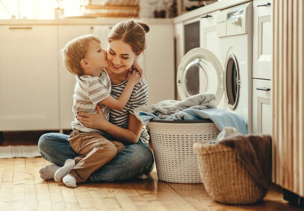 kid kissing mother next to the washing machine