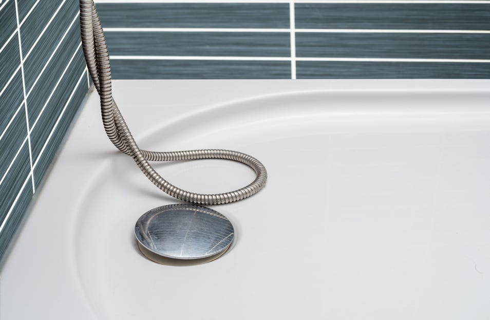 Close-up of a metal shower drain on a clean white shower floor