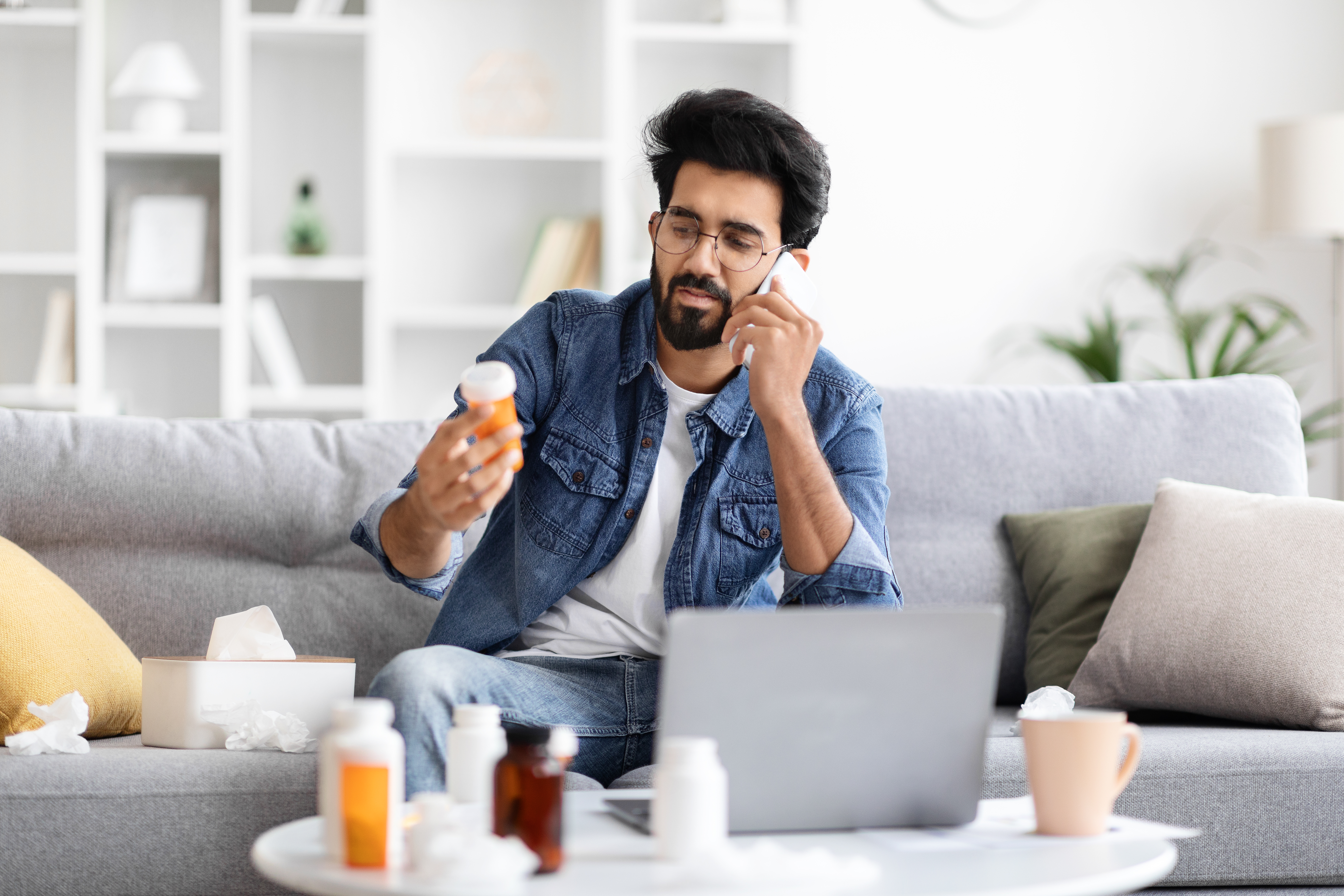 A man talking on the phone, holding OTC medication for cold and flu