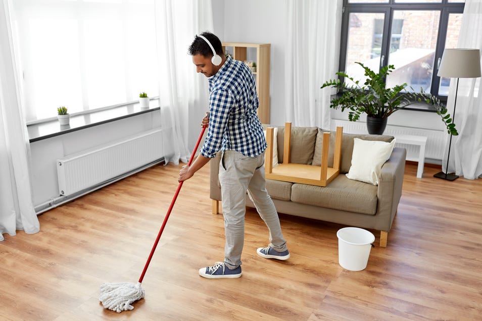 Man wearing headphones mopping hardwood floors
