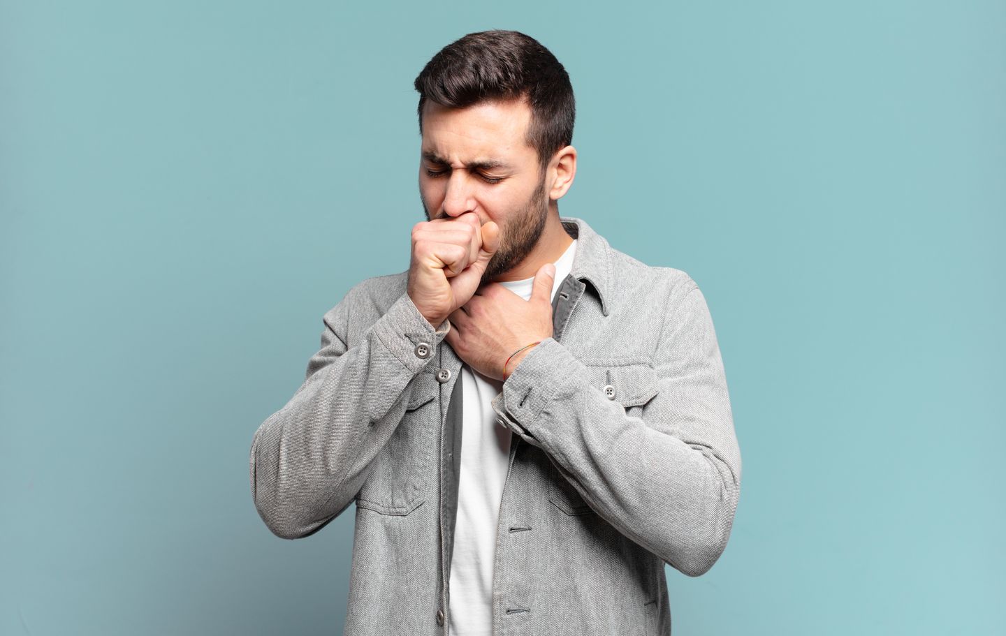 A man holding his throat while coughing at the same time