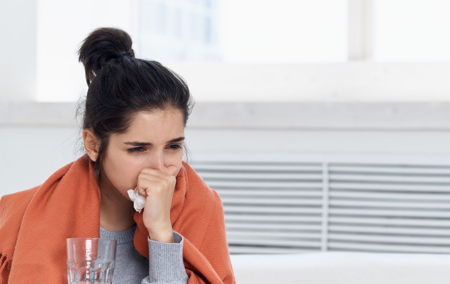Sick woman with flu and runny nose sitting with a scarf around her