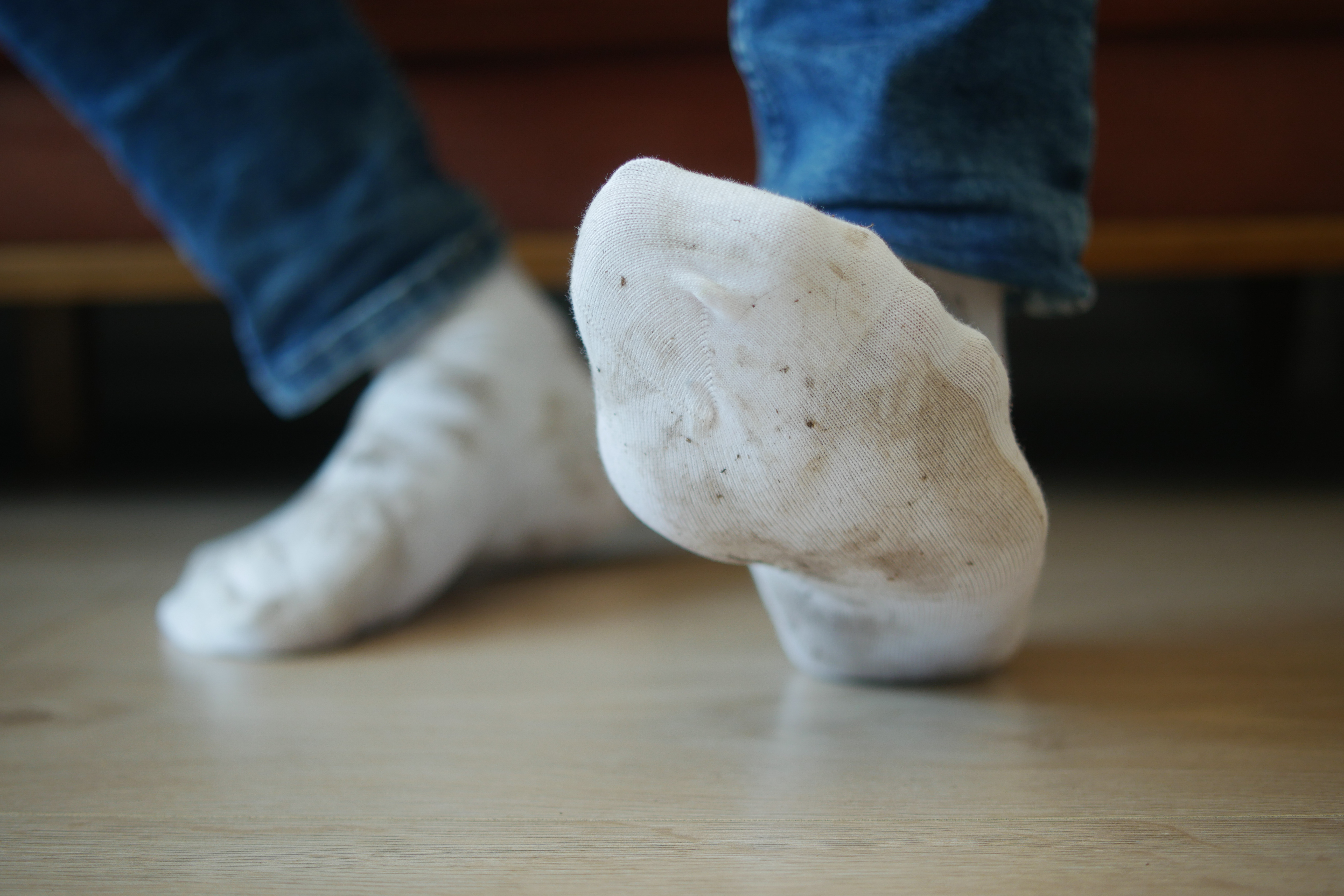 Person wearing dirty white socks and blue jeans