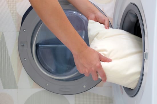Person putting a pillow into a washing machine