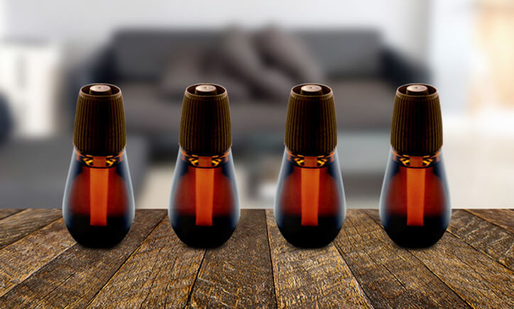 Displays four bottles of Essential Mist® single refills on a table placed in a line.