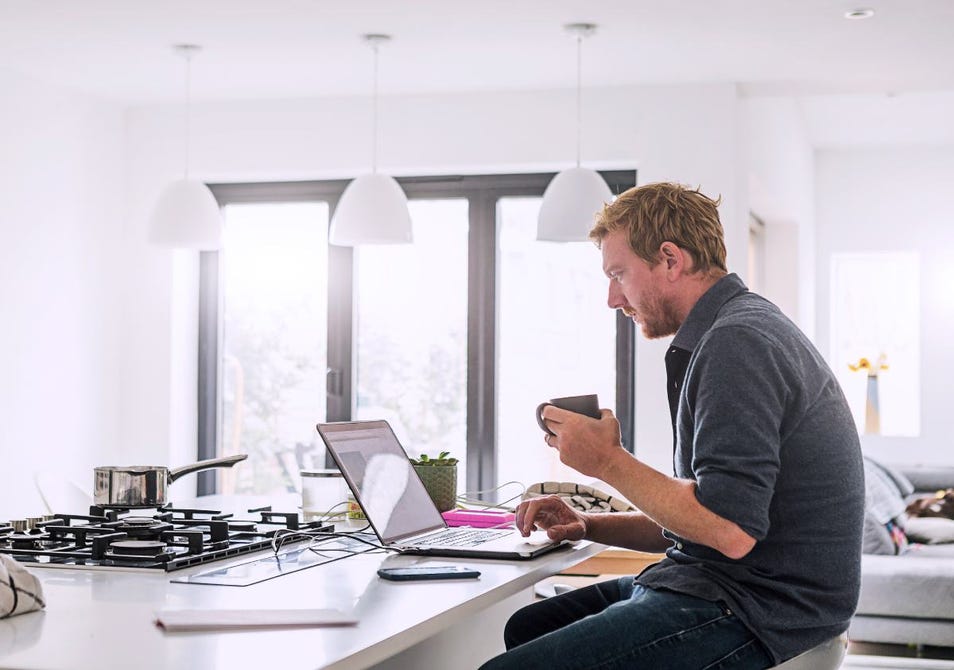 man working on his laptop in kitchen
