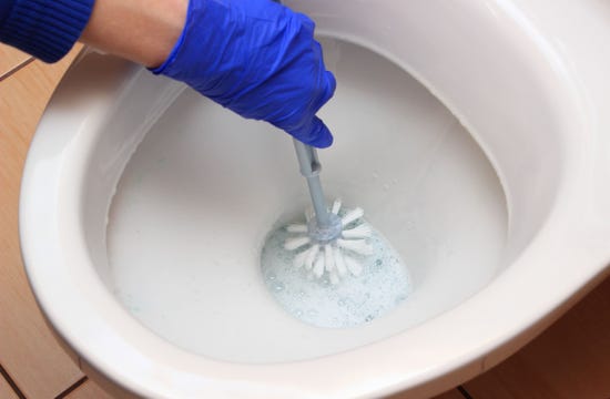 Someone cleaning the inside of a toilet bowl