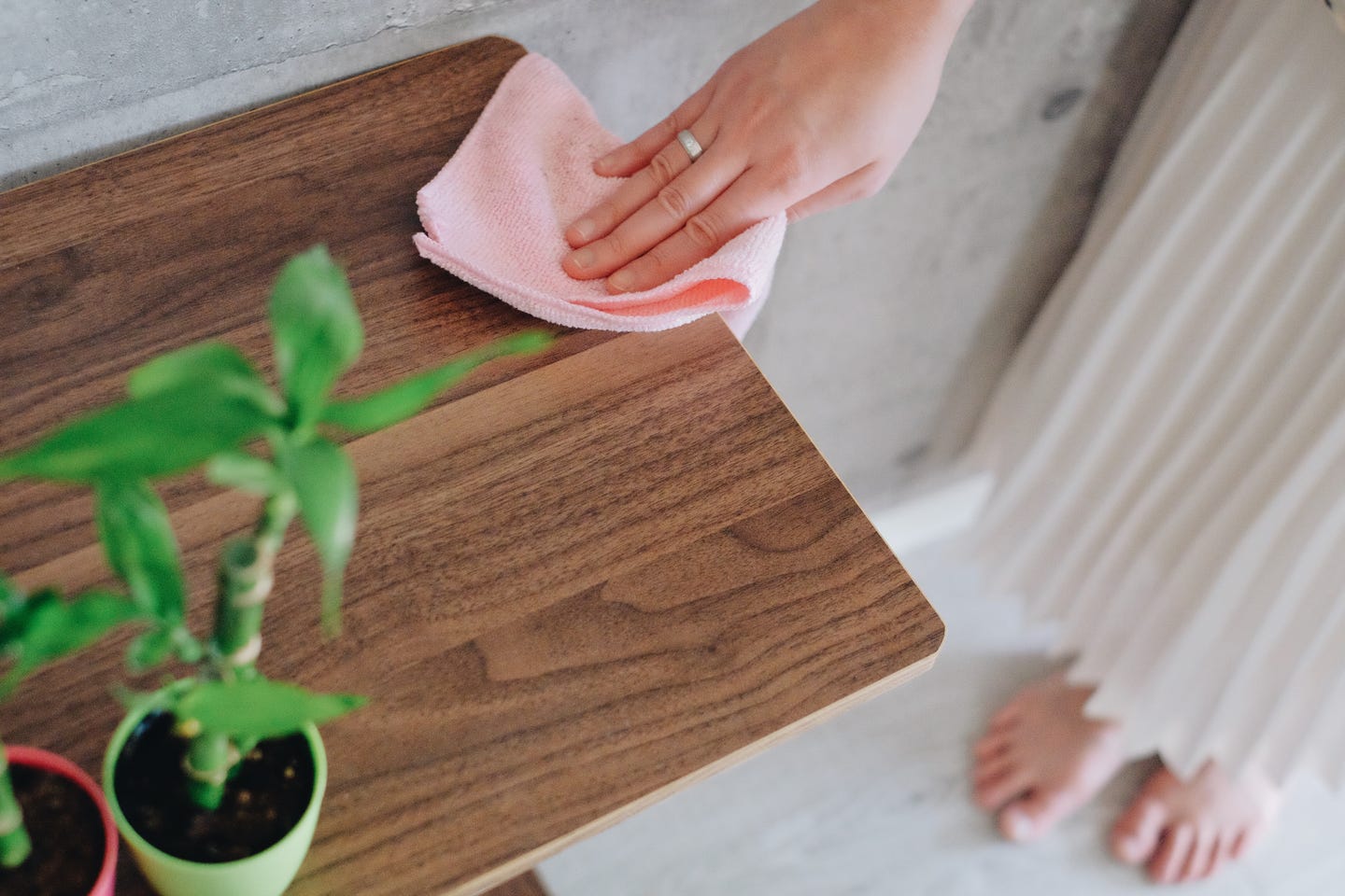 A hand wiping a wooden table with a microfiber cloth