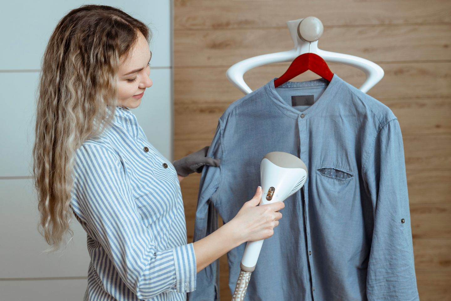 A woman steaming a shirt with a steamer
