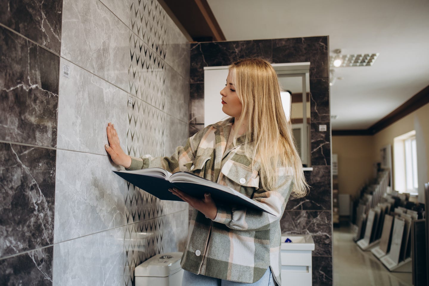 A woman holding a book and placing her hand on a tile