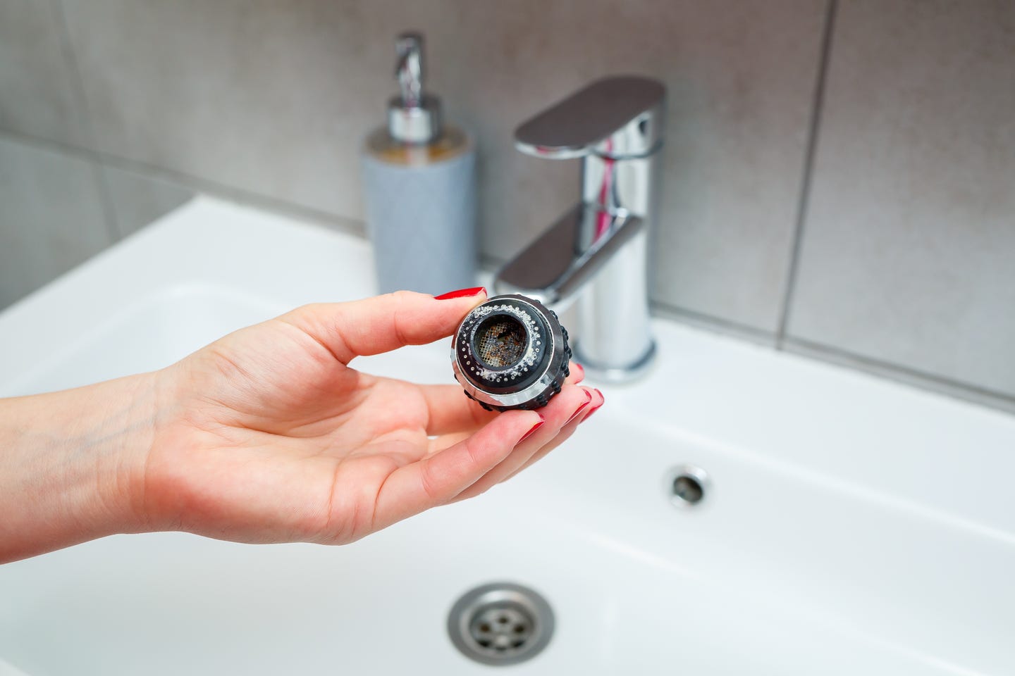 close-up of a woman's hand holding a dirty faucet aerator