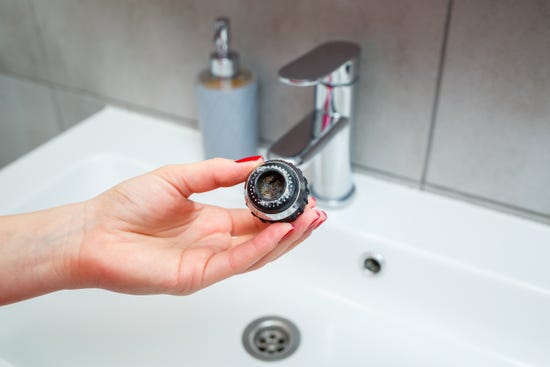 close-up of a woman's hand holding a dirty faucet aerator