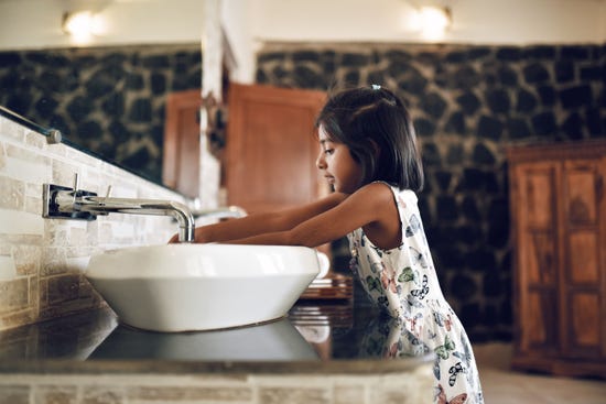 A little girl washing hands at the sink