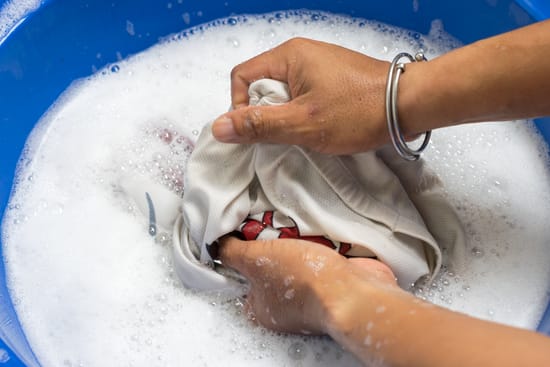 Person washing clothes by hand in soapy water