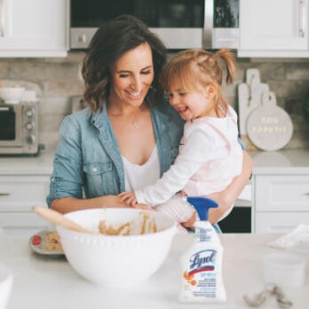 Woman and child looking at a bowl, with Lysol Simply All Purpose Cleaner - Orange Blossom on the side