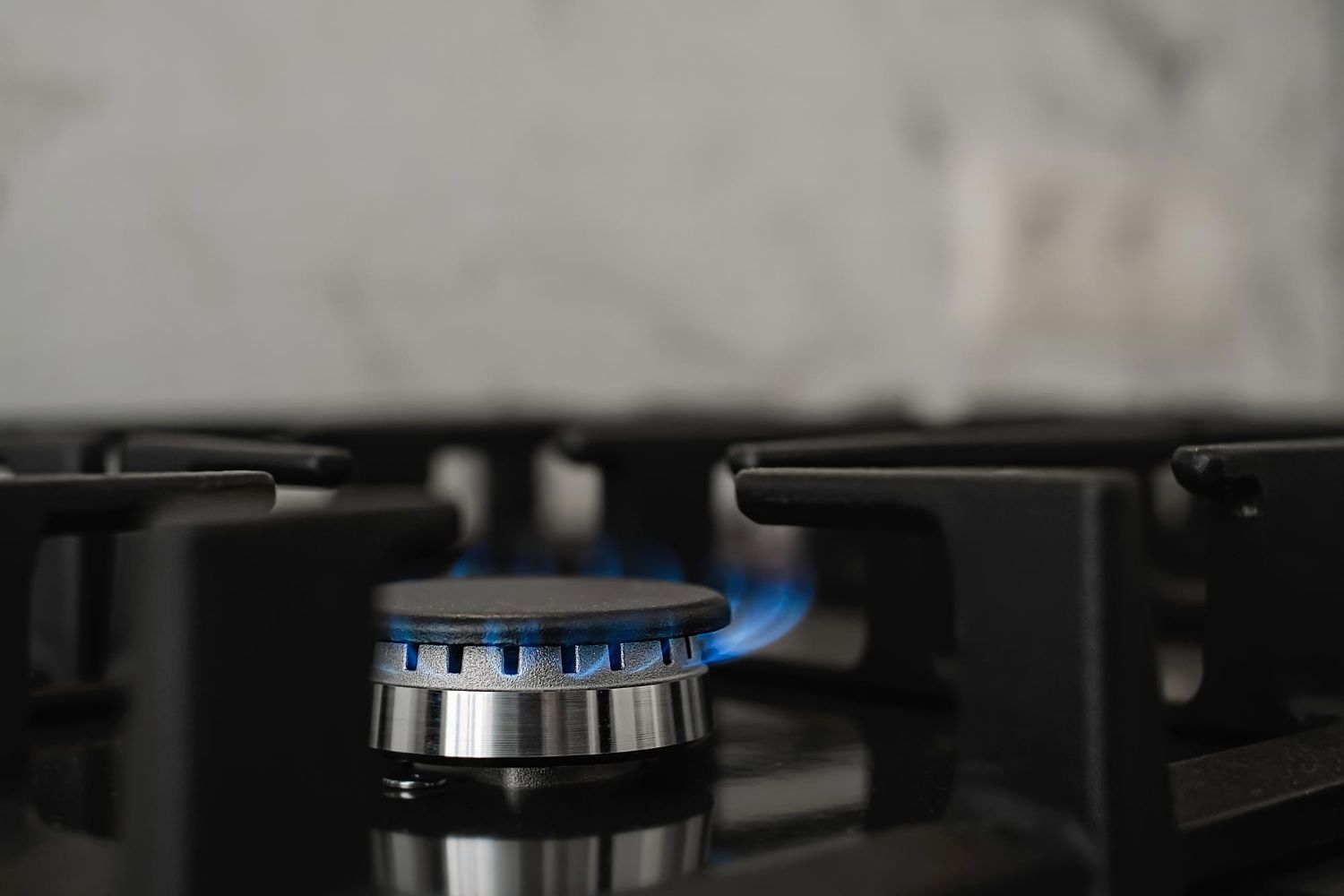 Chama azul acesa em boca de fogão a gás durante o preparo de alimentos.