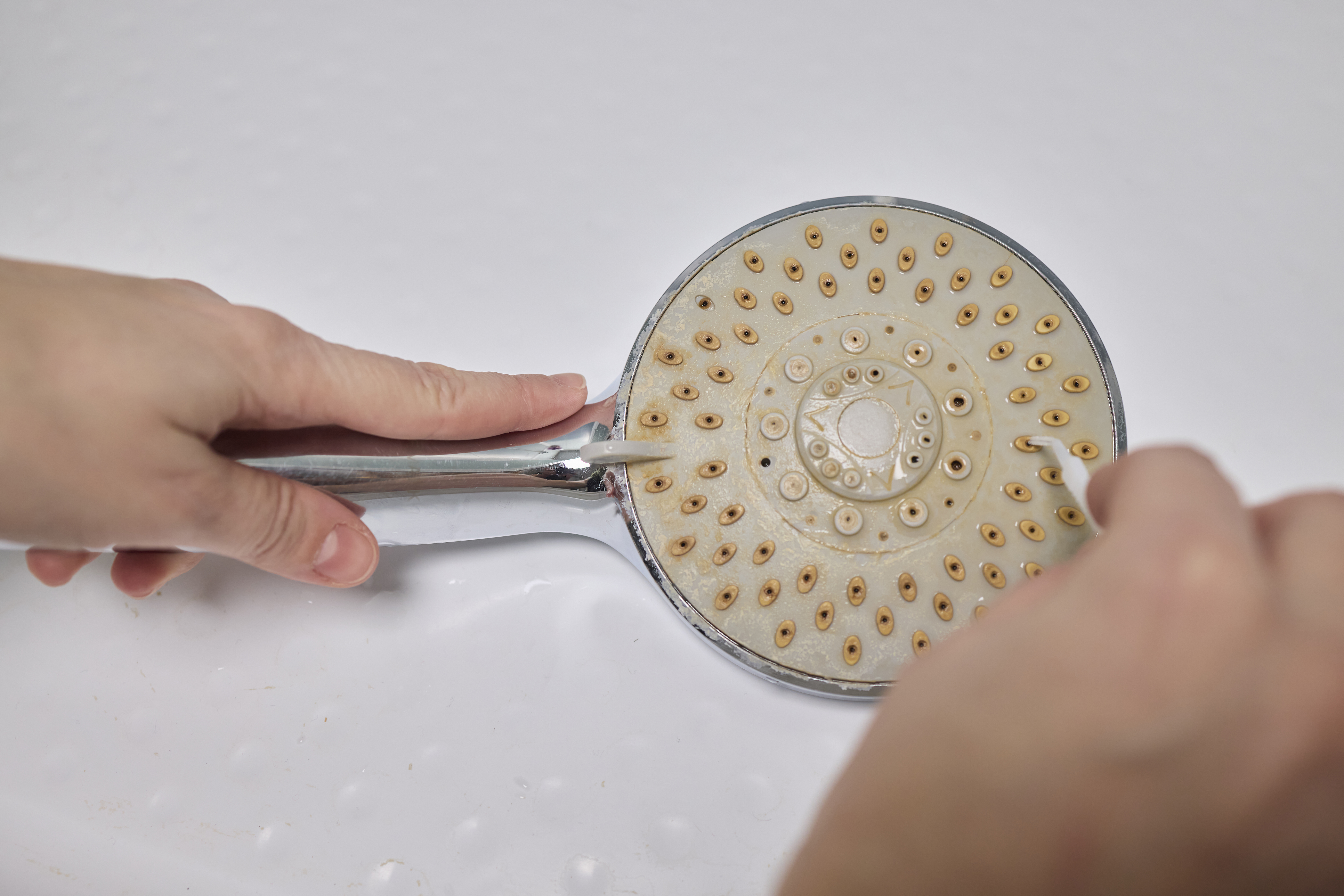A person cleaning a shower head