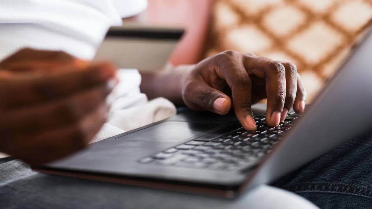 Man's hands holding a credit card while working on a laptop. 