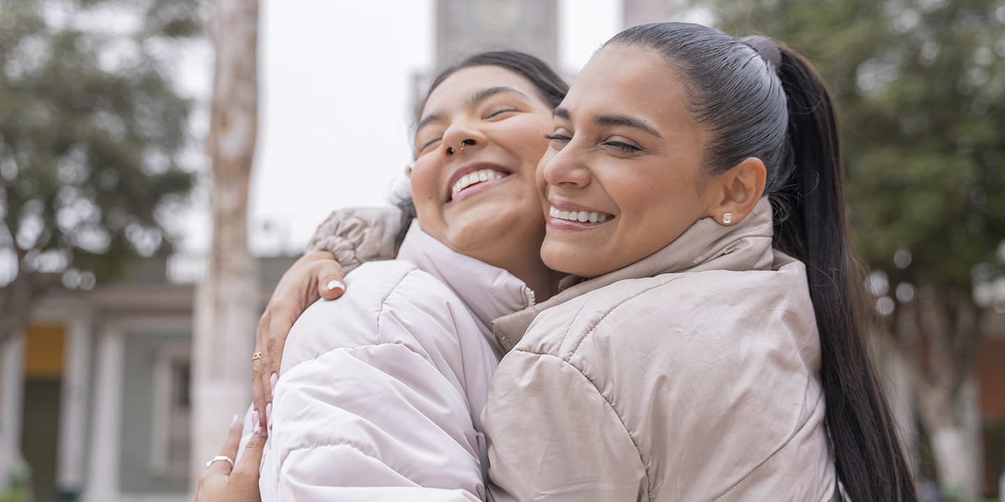 Abrazo entre mujeres adultas en mitad de la calle