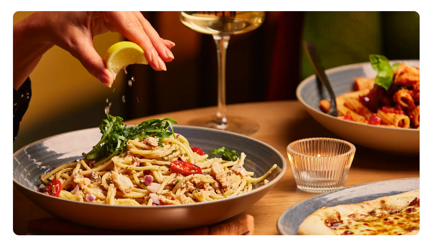 Spaghetti carbonara with a lemon being squeezed on top