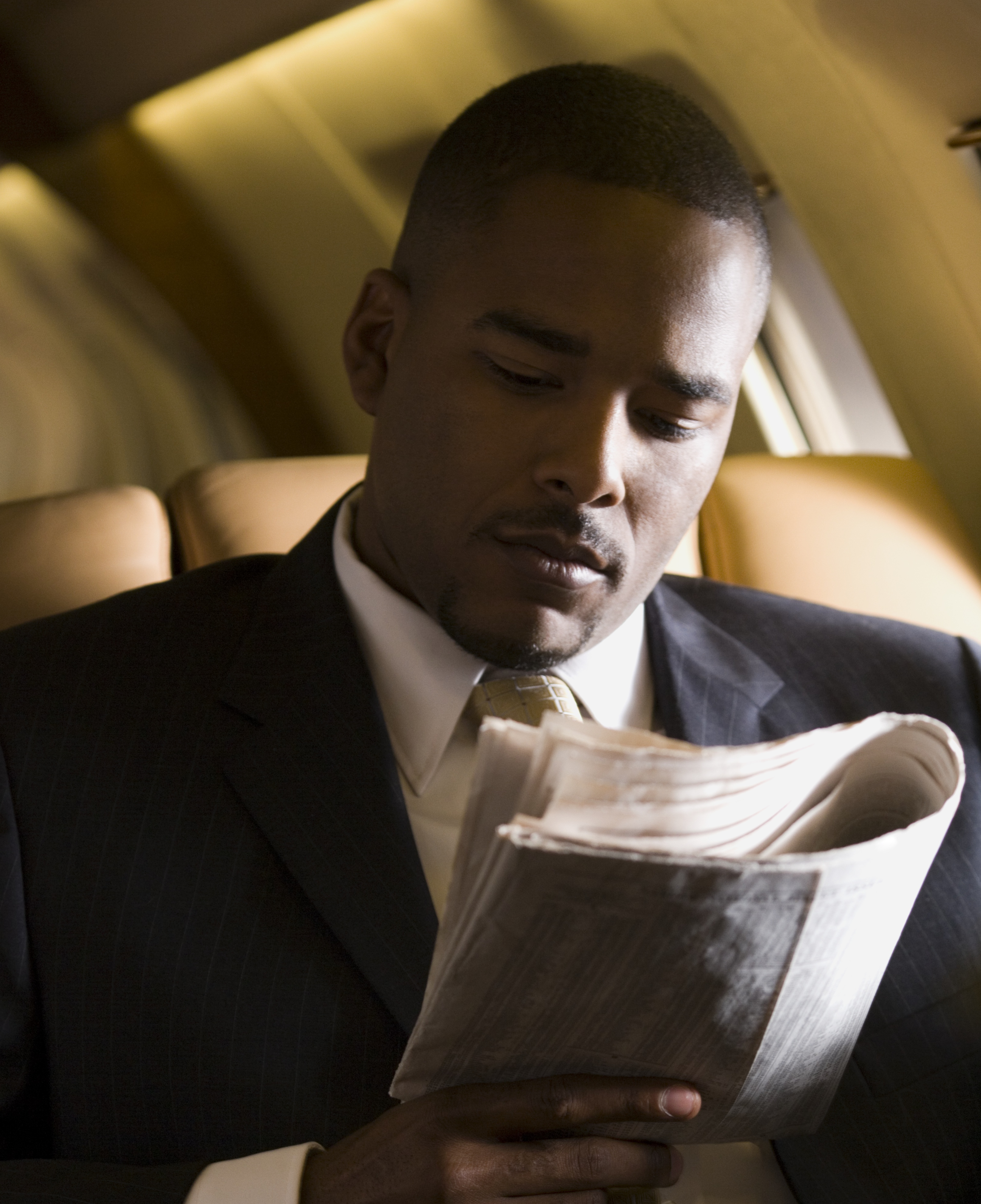 Business man reading a newspaper on an airplane