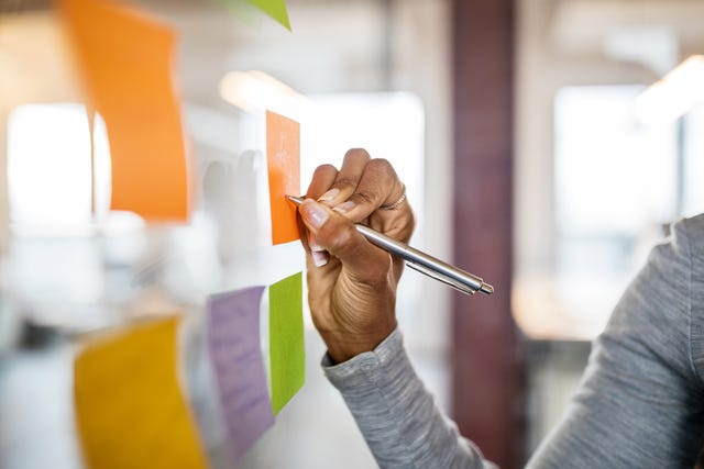 Female writing on a sticky note