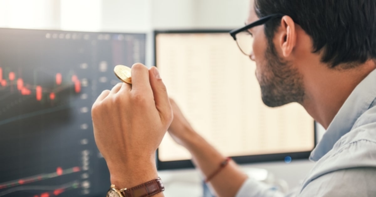 man_looking_at_monitor_with_coin_in_hand.jpg