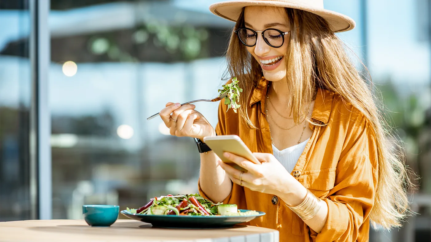 Woman eating a salad while checking the phone Woman eating a salad while checking the phone
