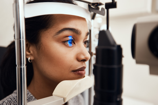 A woman has her eye scanned by an optometrist.