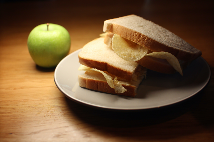 A crisp sandwich and an apple on a plate