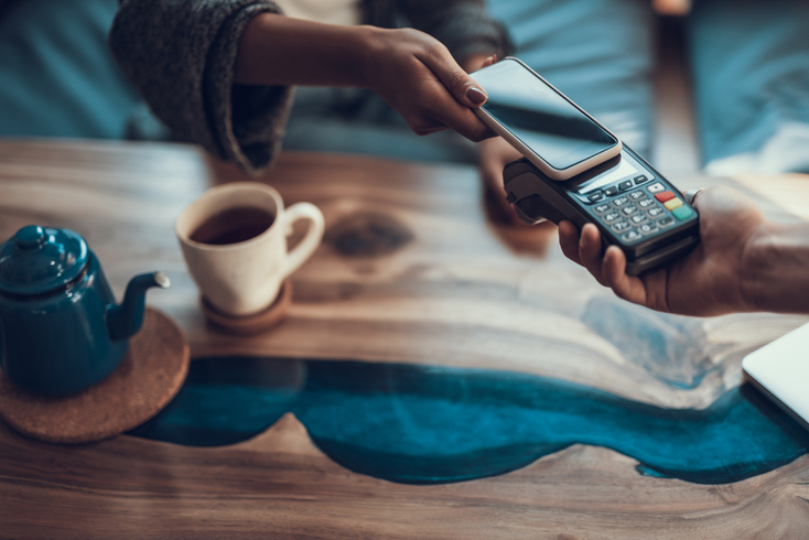 Person paying for a coffee with a cell phone Person paying for a coffee with a cell phone
