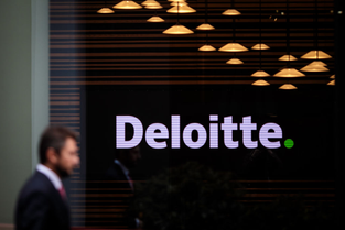 A person walks past a Deloitte-branded office. 