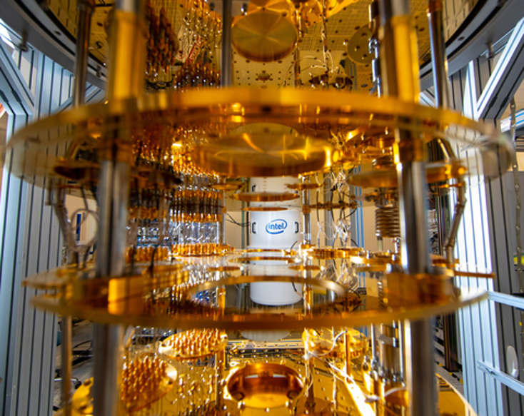 An Intel quantum computer in a golden chandelier configuration with the Intel logo on the wall behind it