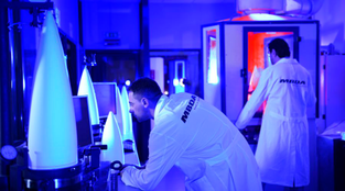Engineers work on missiles in a lab in blue light