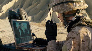 A solider using a laptop and phone