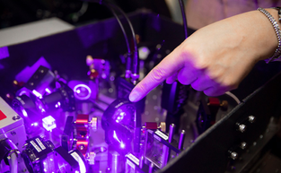A researcher points at purple-lit technology