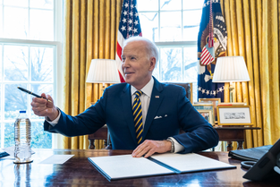 President Biden signs documents at his Oval Office desk
