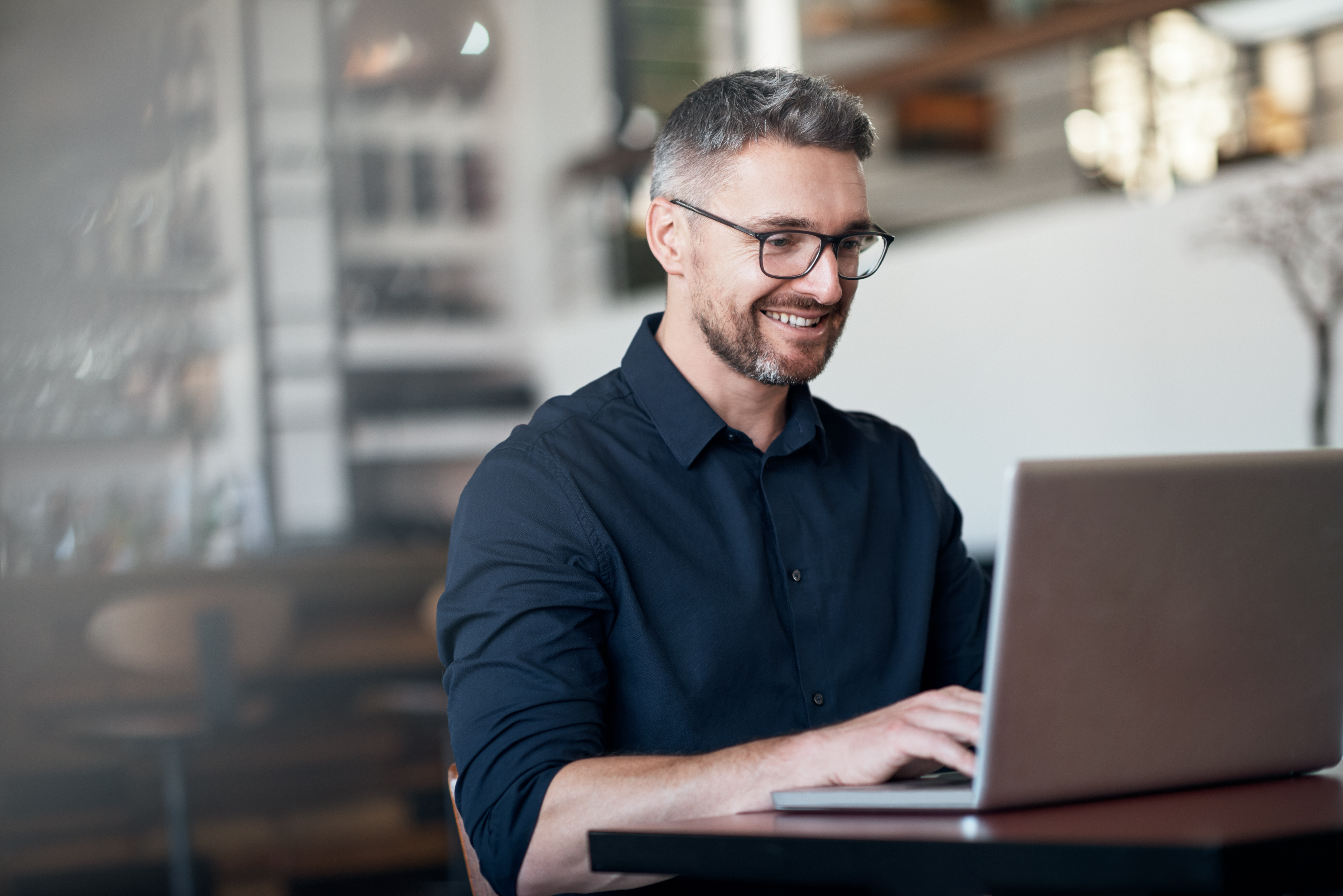 Man with glasses working on a laptop