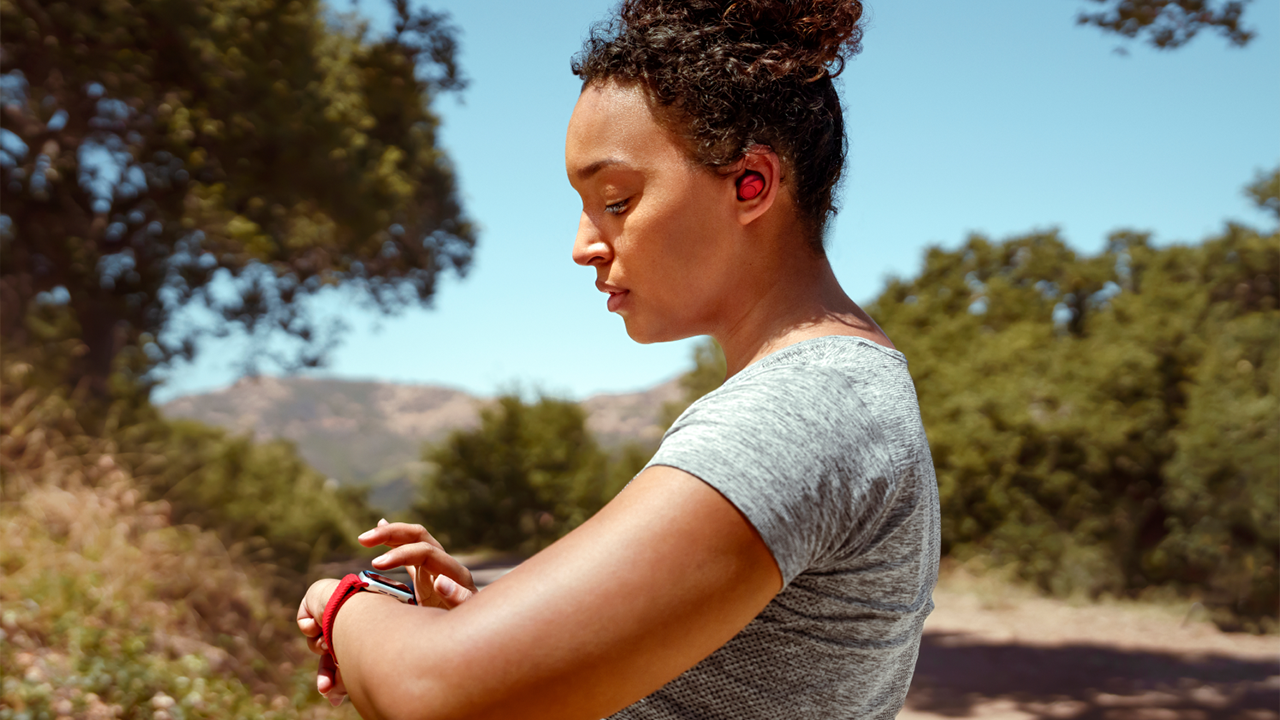 a woman with ear plugs in and clicking on her a watch