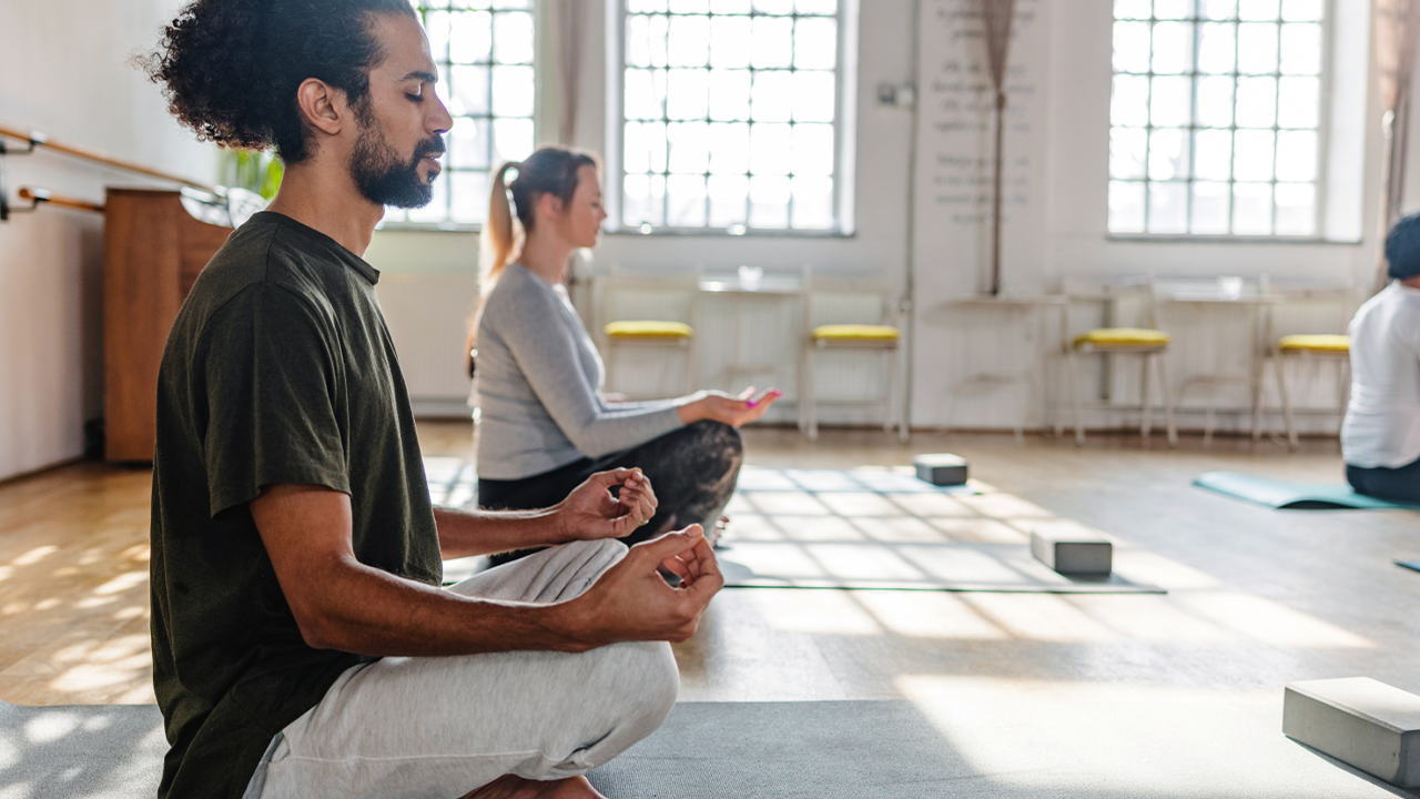 A man and a woman doing yoga with eyes closed