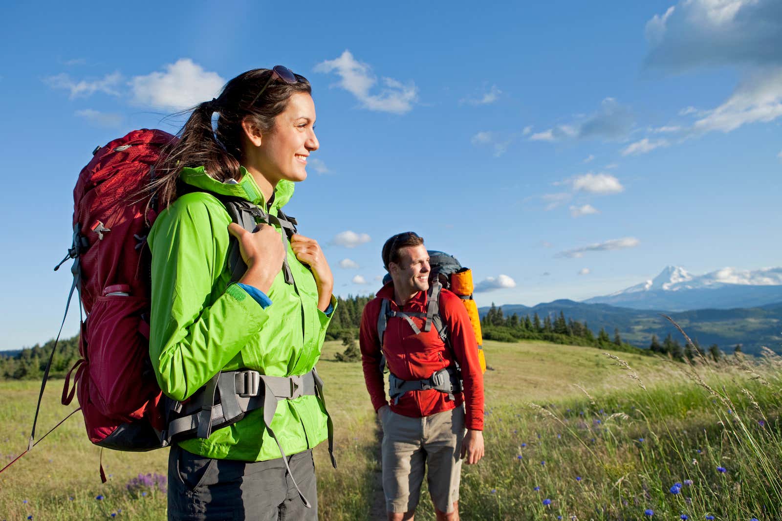 A man and a woman carrying both of them a backpack and walking in the nature