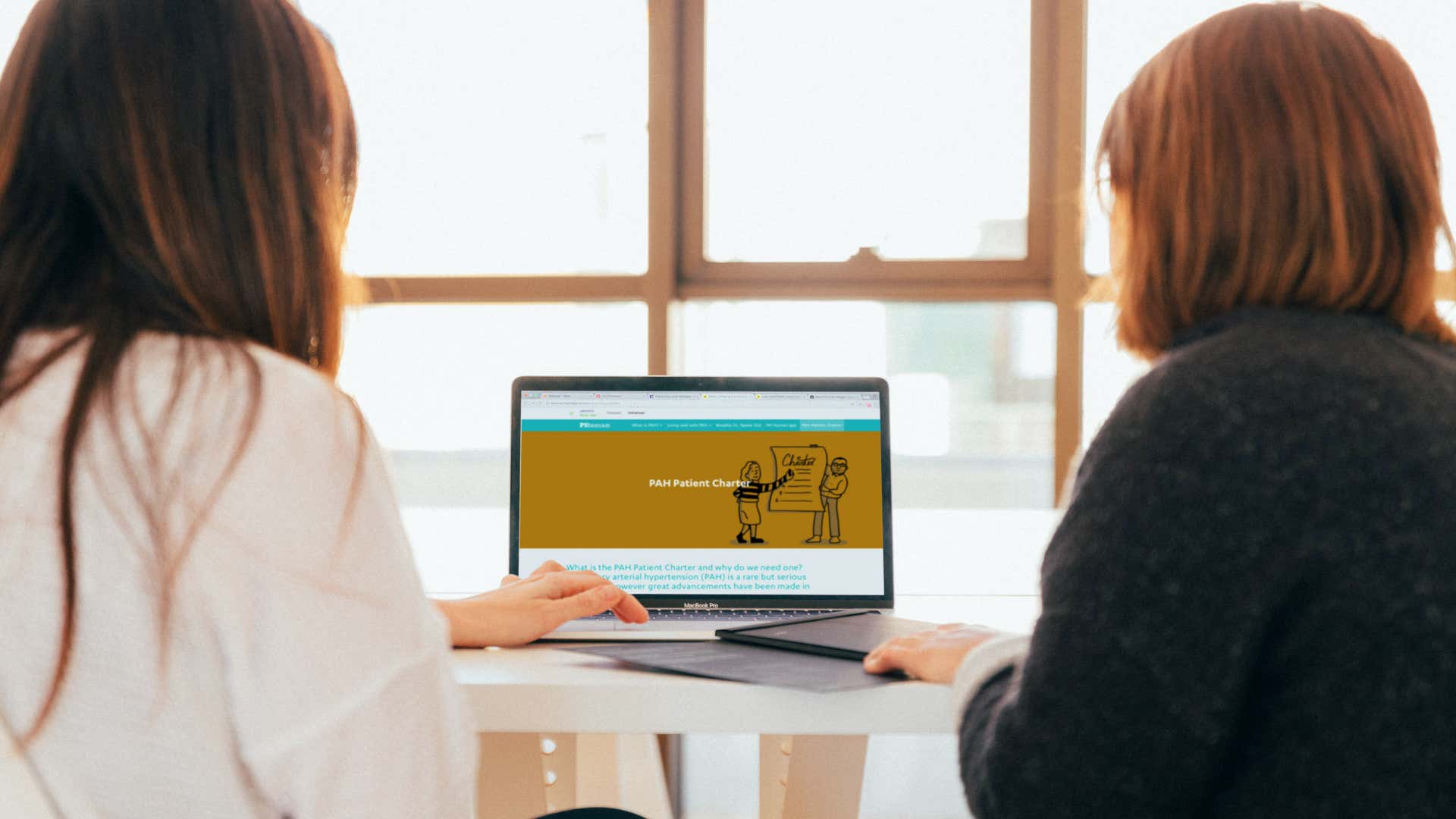 Two women viewing PAH Patient Charter on a laptop