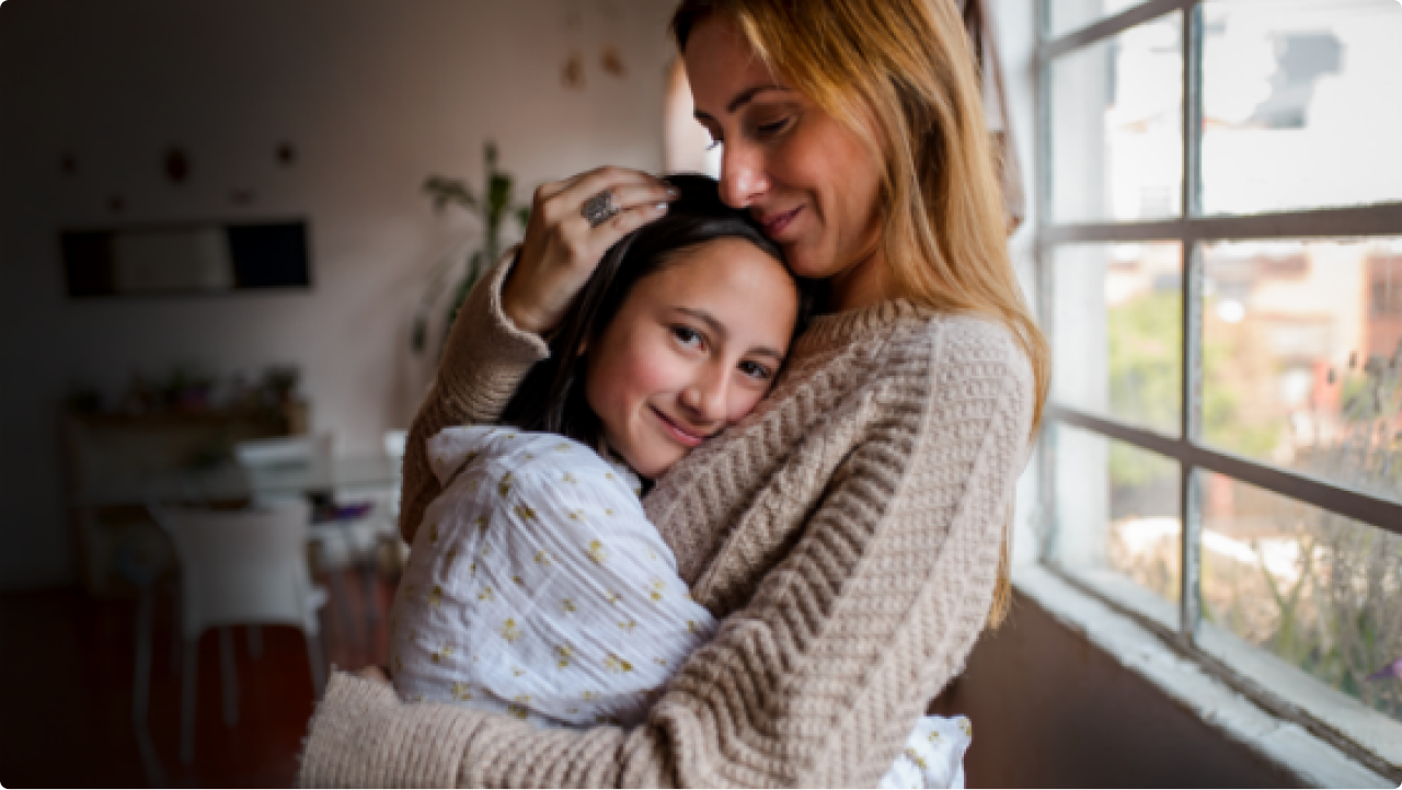 Mom hugging a daughter near a window