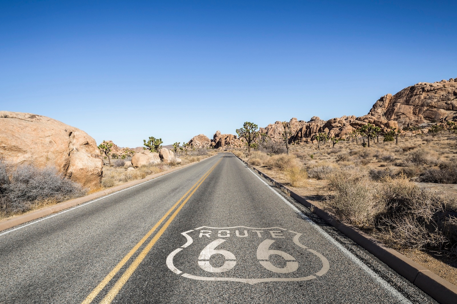 A road featuring a painted Route 66 sign, symbolizing the historic highway and American road trip culture