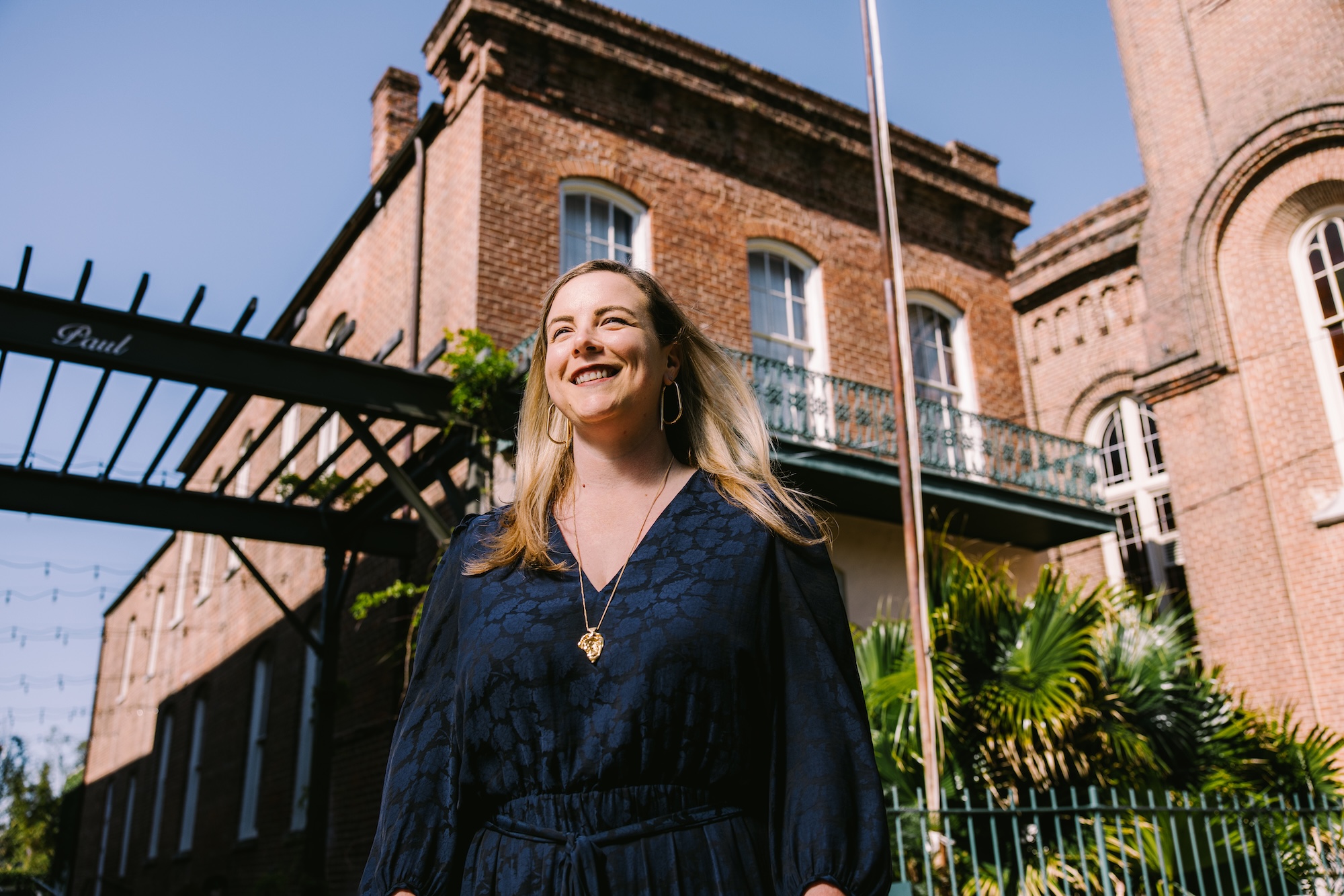 A woman in a blue top stands in front of a building in NOLA
