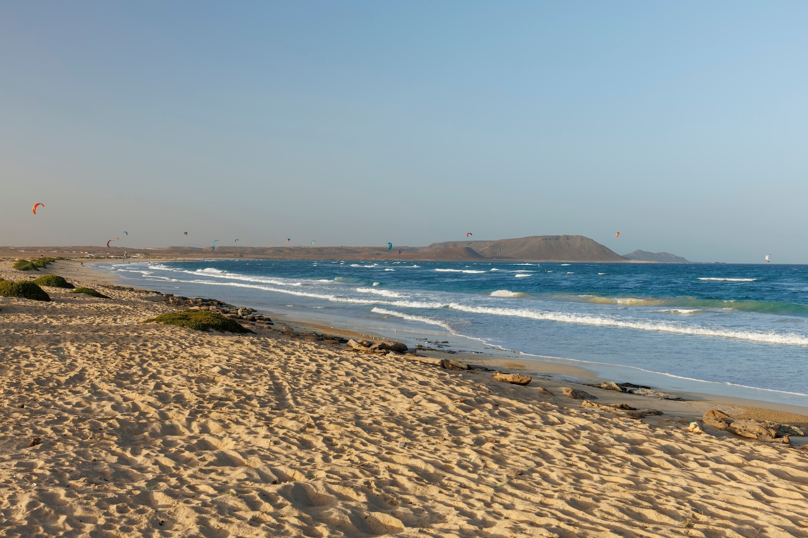 A scenic sandy beach in Sal, Cape Verde, with gentle waves lapping at the shore under a clear blue sky