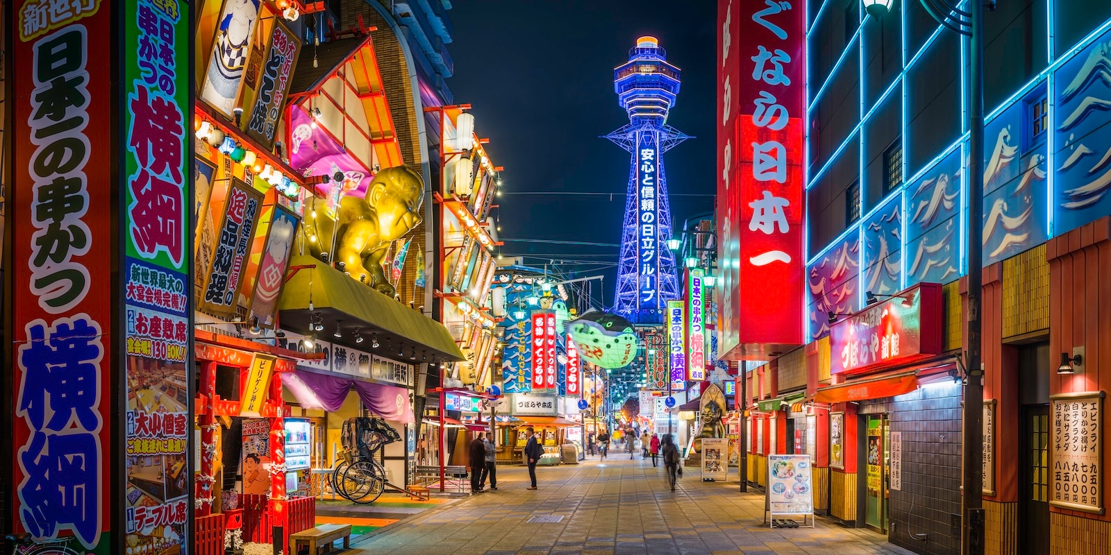 A vibrant city street in Shin-Osaka featuring colourful buildings and a prominent tall tower