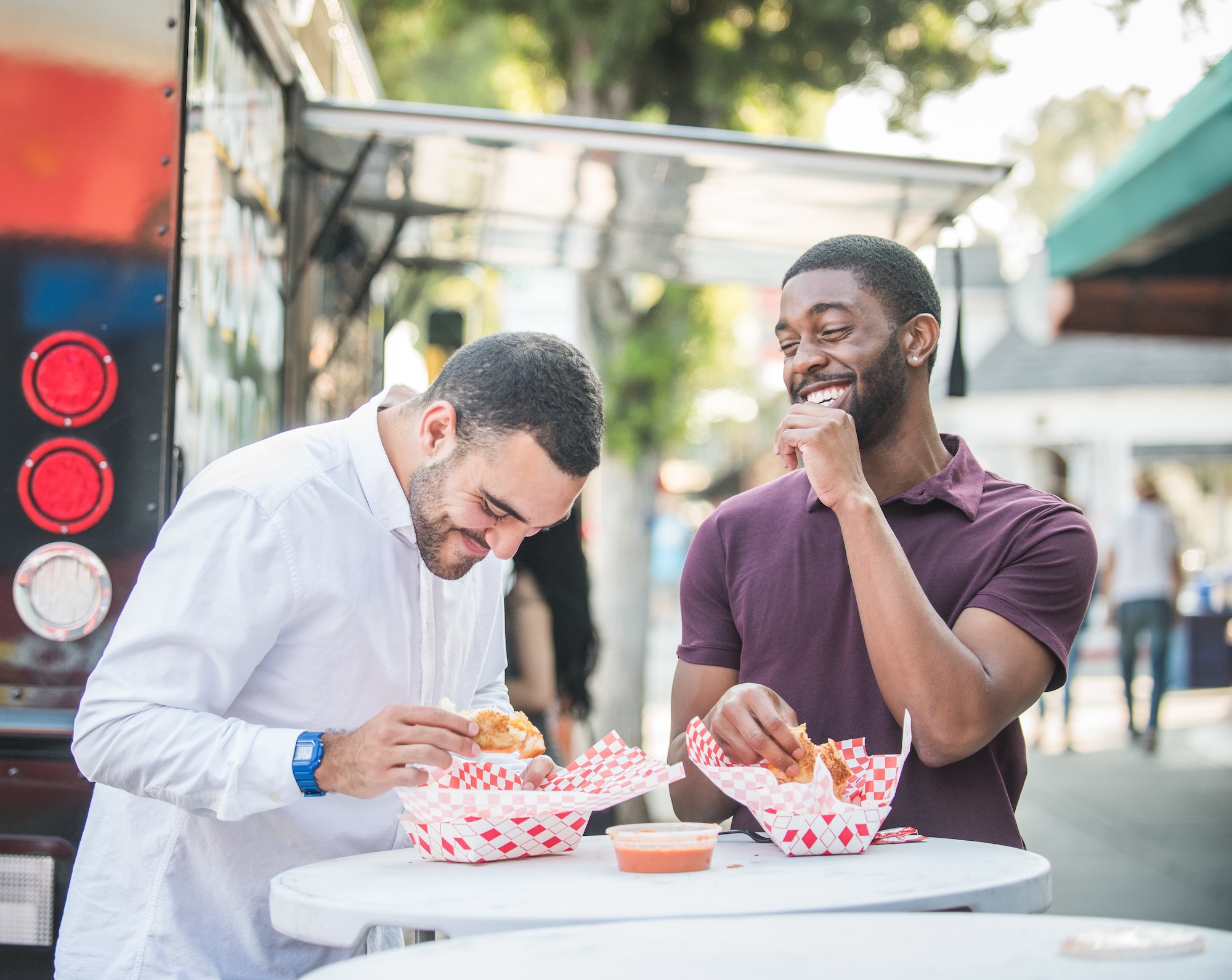 Two men joyfully eat some food from the US