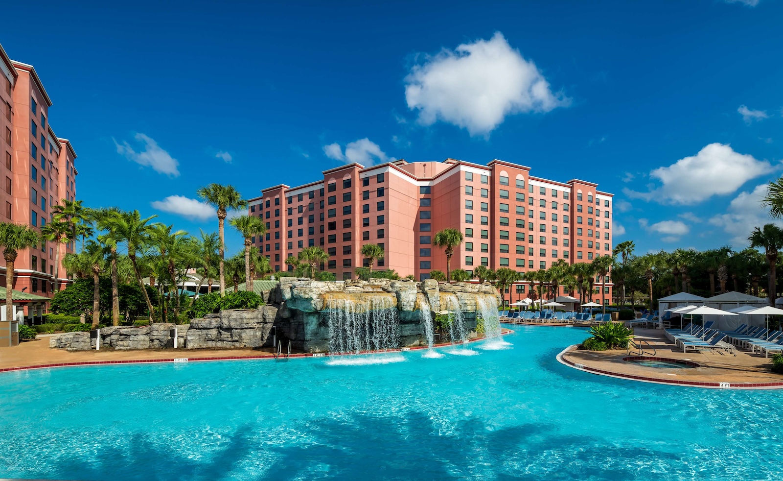 Resort pool at Caribe Royale Orlando, featuring clear blue water surrounded by palm trees and lounge chairs
