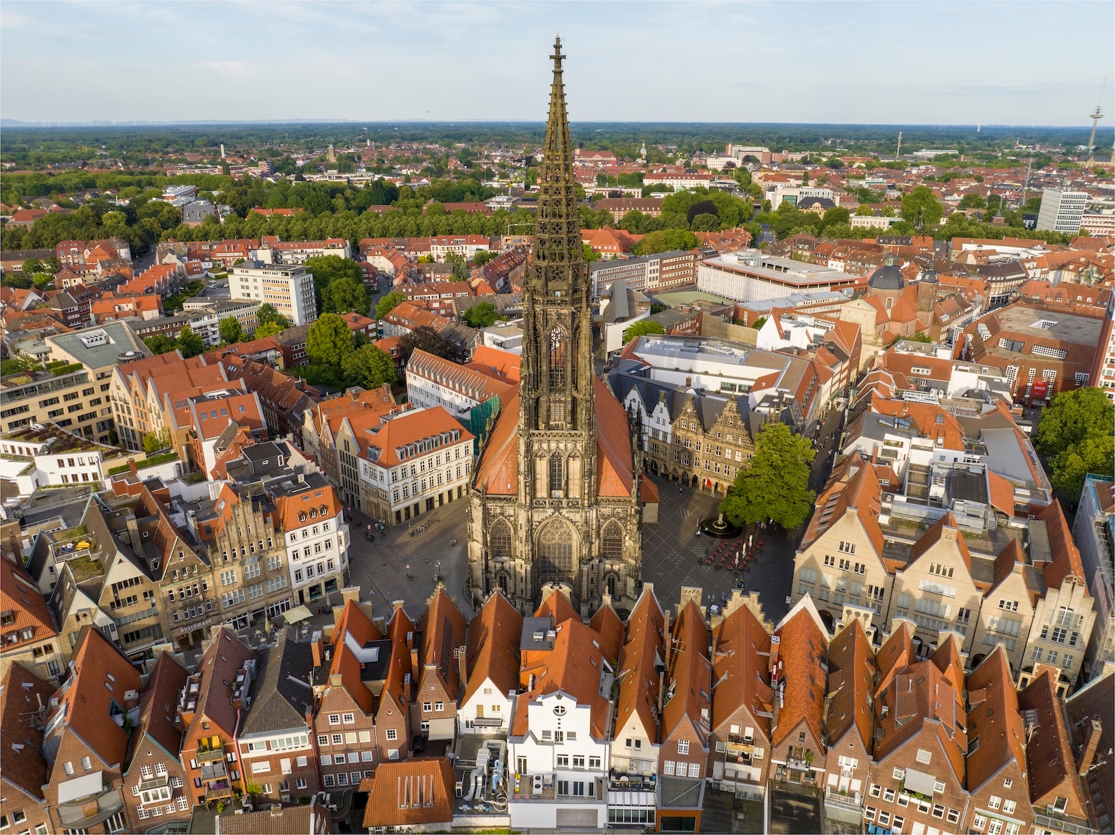 Aerial view of Münster, Germany, featuring the prominent St. Lamberti church tower amidst the cityscape.